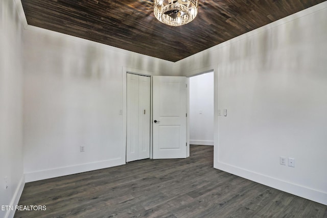 unfurnished room with dark hardwood / wood-style floors, a notable chandelier, and wooden ceiling