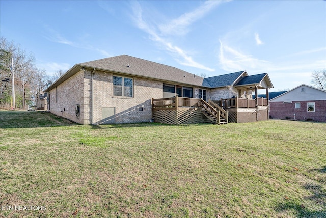 rear view of house with a deck, brick siding, a lawn, and stairs