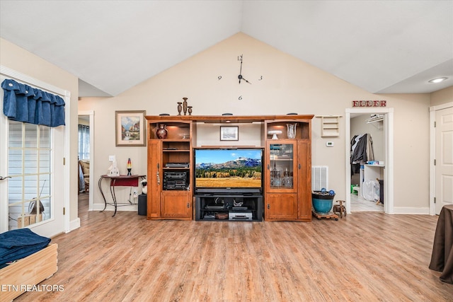 living room featuring light wood-type flooring, visible vents, vaulted ceiling, and baseboards