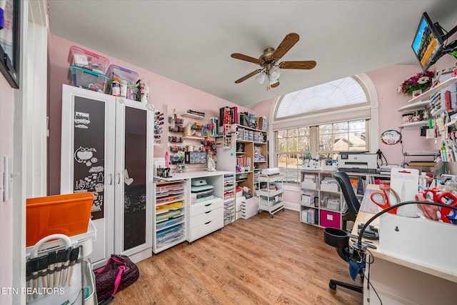 office area with light wood-style floors, ceiling fan, and vaulted ceiling