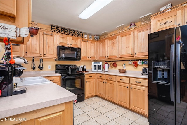 kitchen with light tile patterned floors, black appliances, a sink, and light countertops