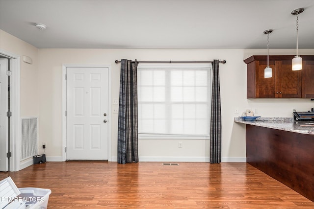 kitchen featuring light stone countertops, visible vents, pendant lighting, and wood finished floors