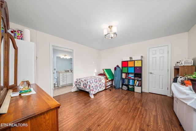 bedroom with connected bathroom, an inviting chandelier, and wood finished floors