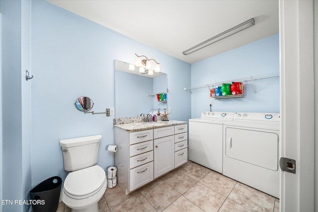 bathroom featuring toilet, tile patterned floors, vanity, and washing machine and clothes dryer