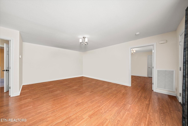 empty room featuring baseboards, visible vents, and wood finished floors