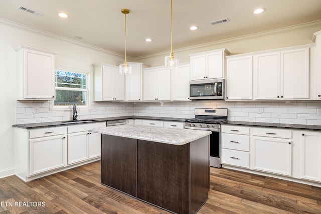 kitchen with decorative light fixtures, sink, white cabinetry, dark hardwood / wood-style floors, and stainless steel appliances