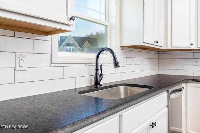 kitchen with white cabinets, tasteful backsplash, stainless steel dishwasher, and sink