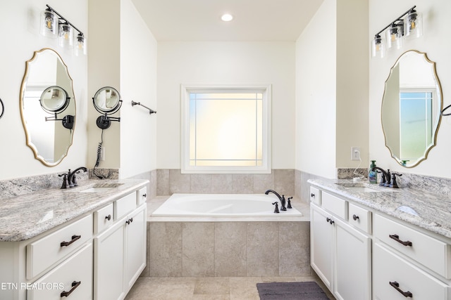 bathroom with tiled bath, tile patterned floors, and vanity