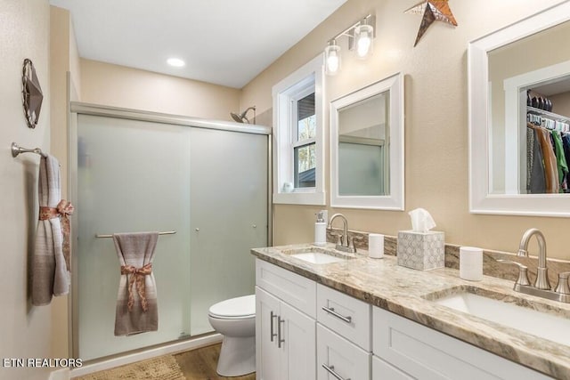 bathroom with toilet, hardwood / wood-style flooring, a shower with door, and vanity