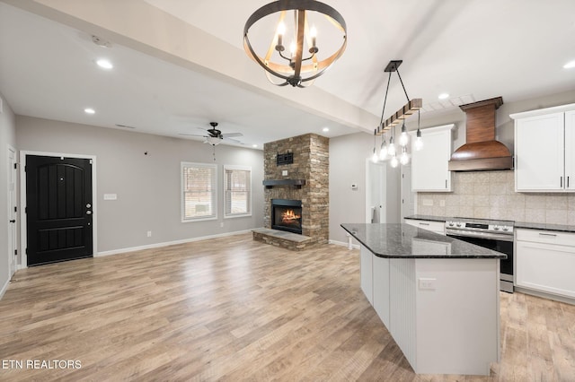 kitchen featuring custom exhaust hood, hanging light fixtures, stainless steel range with electric stovetop, white cabinets, and dark stone counters