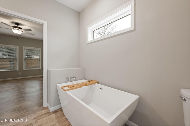 bathroom featuring toilet, wood-type flooring, a washtub, and ceiling fan