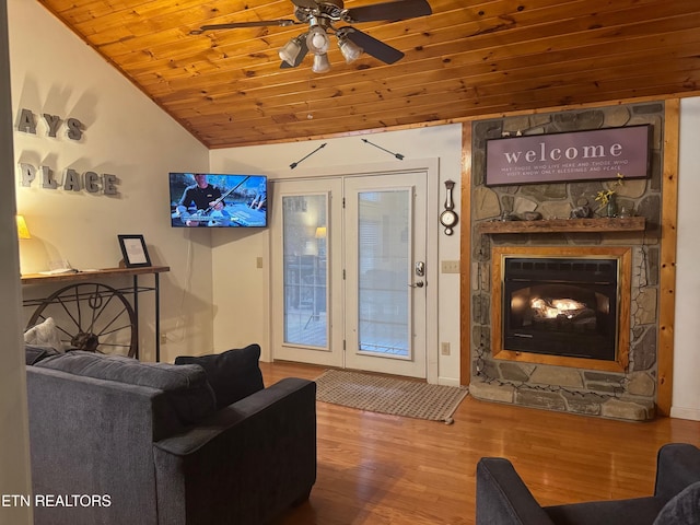 living room with lofted ceiling, a stone fireplace, wood-type flooring, wooden ceiling, and ceiling fan