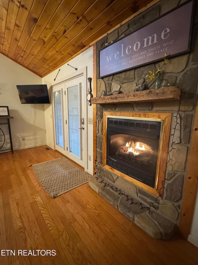 interior space with hardwood / wood-style flooring, a stone fireplace, and wooden ceiling