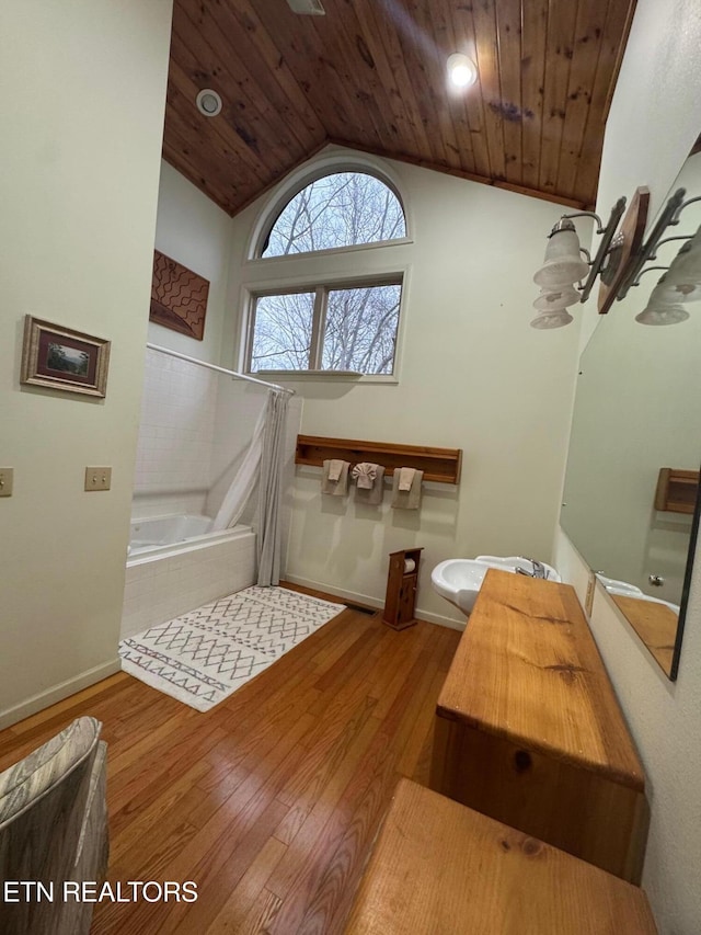 bathroom featuring lofted ceiling, hardwood / wood-style floors, wood ceiling, and tiled bath