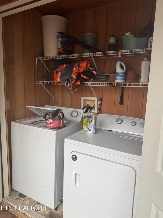 laundry room featuring washing machine and clothes dryer and wood walls