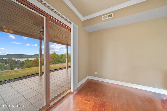 doorway to outside featuring light hardwood / wood-style flooring, ornamental molding, and a water view