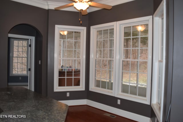 unfurnished dining area featuring visible vents, baseboards, ceiling fan, arched walkways, and dark wood finished floors