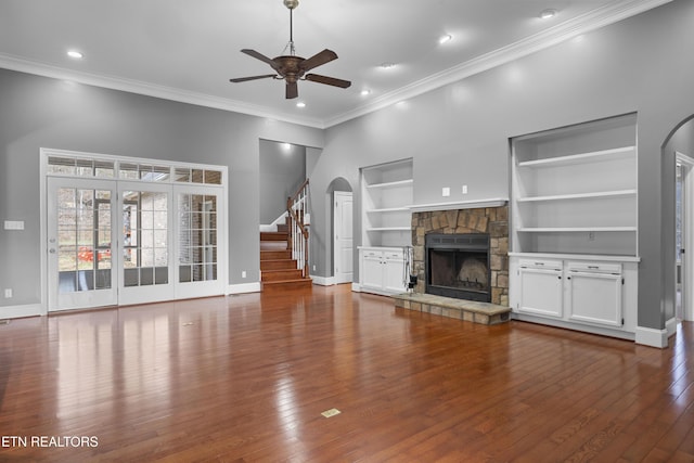 unfurnished living room featuring baseboards, a ceiling fan, built in features, and a stone fireplace