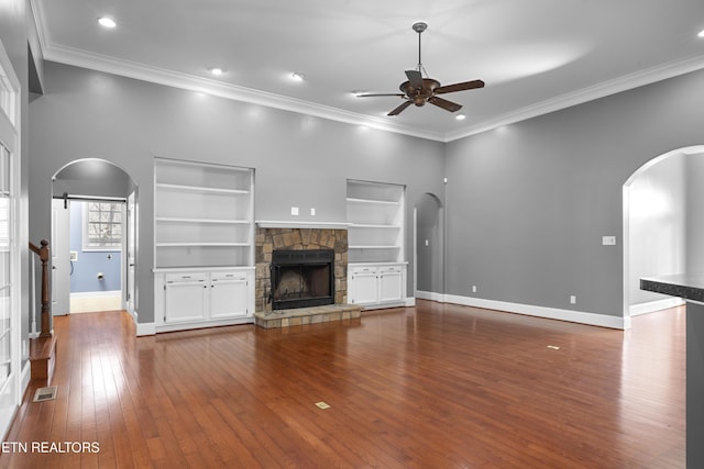 unfurnished living room featuring arched walkways, a ceiling fan, baseboards, visible vents, and dark wood-style floors