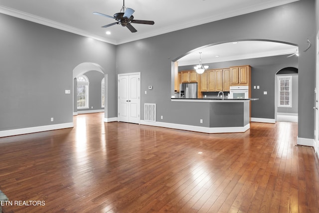 unfurnished living room with plenty of natural light, a ceiling fan, dark wood-style flooring, and visible vents