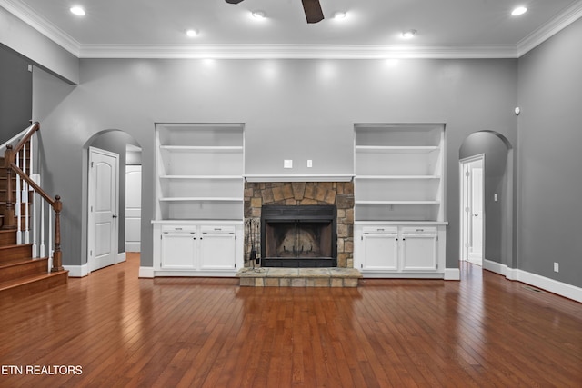 unfurnished living room featuring arched walkways, built in features, stairs, and hardwood / wood-style floors