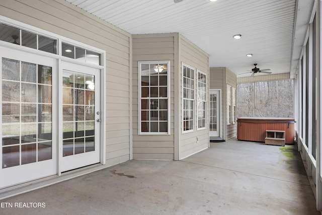 unfurnished sunroom featuring ceiling fan and a hot tub