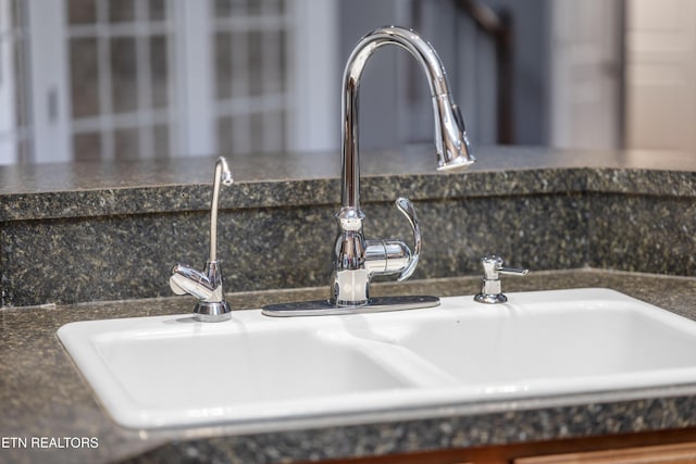 interior details with a sink and dark countertops