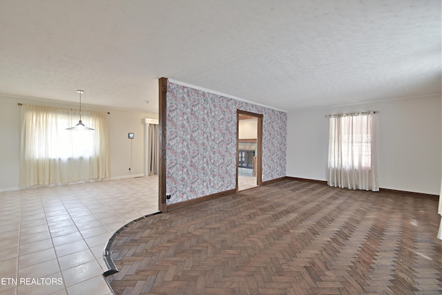 unfurnished room featuring wallpapered walls, a textured ceiling, baseboards, and ornamental molding