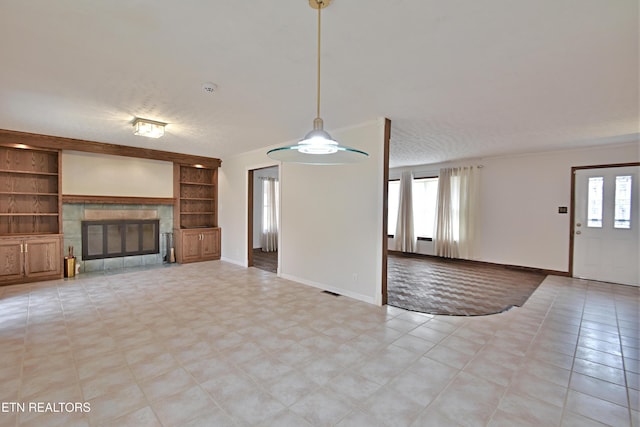 unfurnished living room with a healthy amount of sunlight, a fireplace, and built in shelves