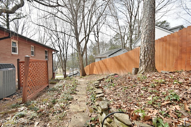 view of yard with central air condition unit and fence