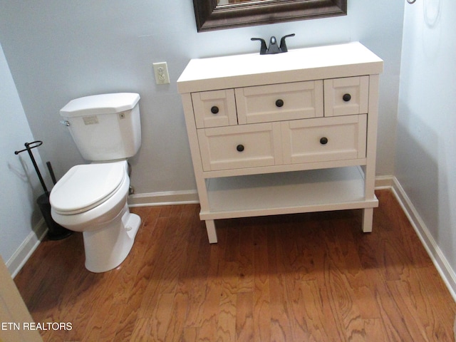 bathroom with hardwood / wood-style flooring, toilet, and vanity