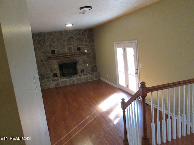 unfurnished living room with vaulted ceiling, wood-type flooring, and a stone fireplace