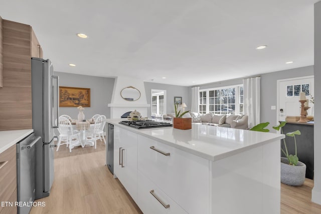 kitchen featuring white cabinetry, a kitchen island, light hardwood / wood-style floors, and appliances with stainless steel finishes