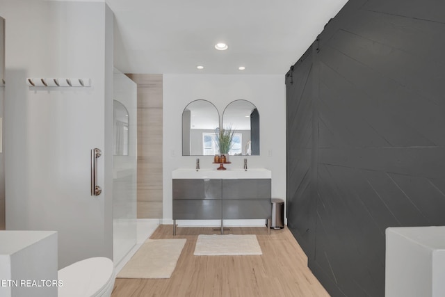 bathroom featuring vanity, wood-type flooring, toilet, and a shower