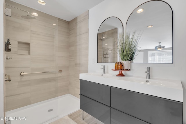 bathroom with a tile shower and vanity