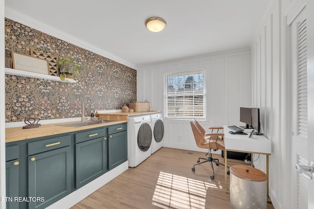 washroom featuring sink, crown molding, cabinets, light hardwood / wood-style floors, and separate washer and dryer