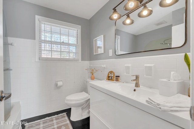 bathroom featuring vanity, toilet, and tile walls