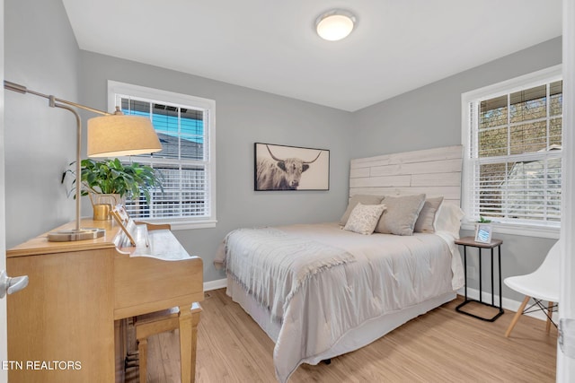 bedroom with multiple windows and light hardwood / wood-style flooring