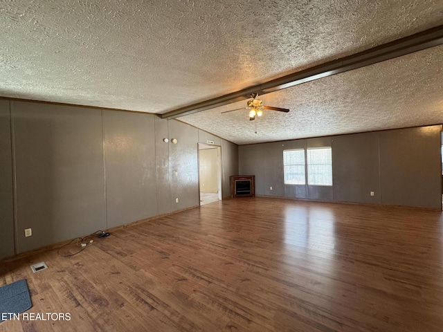 unfurnished living room with ceiling fan, vaulted ceiling with beams, a textured ceiling, and wood-type flooring