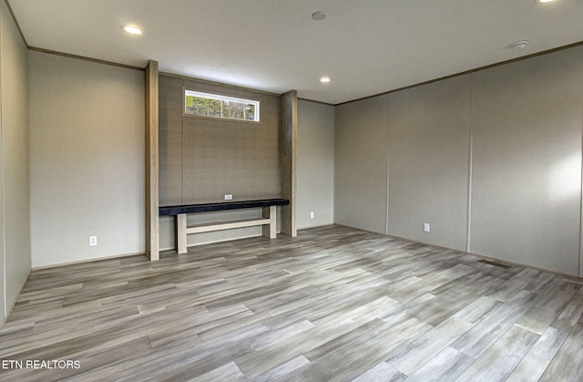 spare room featuring crown molding and light wood-type flooring