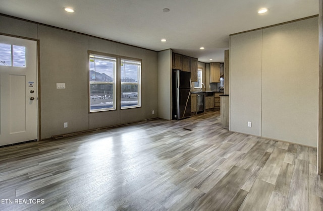 unfurnished living room featuring sink and light hardwood / wood-style flooring