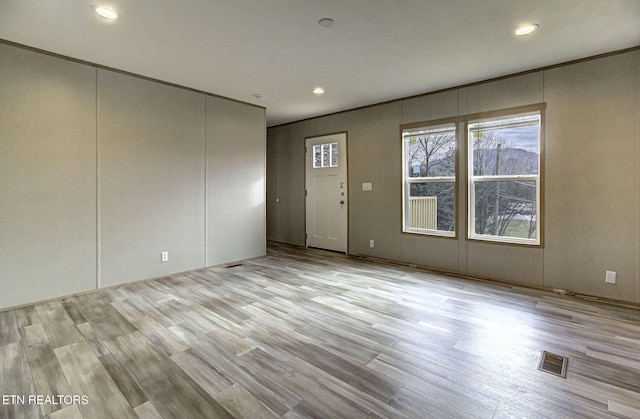 unfurnished room featuring ornamental molding and light hardwood / wood-style floors