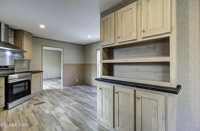 kitchen featuring stainless steel electric stove, light brown cabinets, light wood-type flooring, and wall chimney exhaust hood