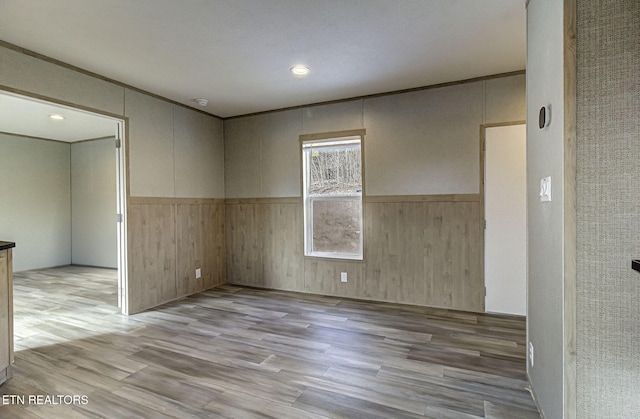 empty room with crown molding and light wood-type flooring