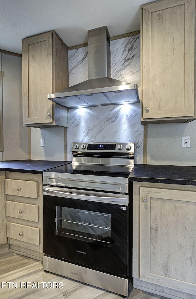 kitchen with crown molding, wall chimney range hood, electric range, and light brown cabinetry