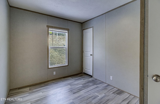 unfurnished bedroom featuring crown molding and light wood-type flooring