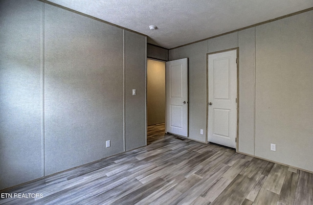 unfurnished bedroom featuring crown molding, light hardwood / wood-style flooring, and a textured ceiling