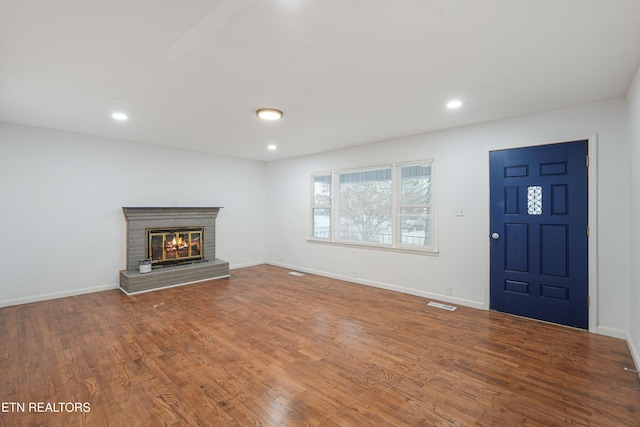 unfurnished living room featuring a brick fireplace and hardwood / wood-style flooring