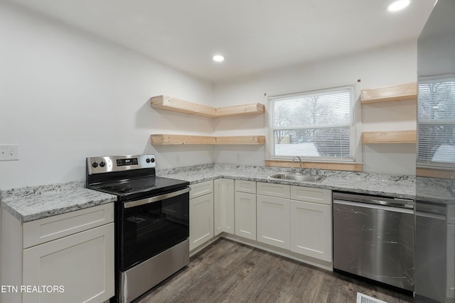 kitchen with sink, white cabinetry, dark wood-type flooring, stainless steel appliances, and light stone counters