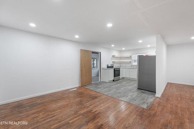 kitchen with white cabinets, appliances with stainless steel finishes, and hardwood / wood-style floors